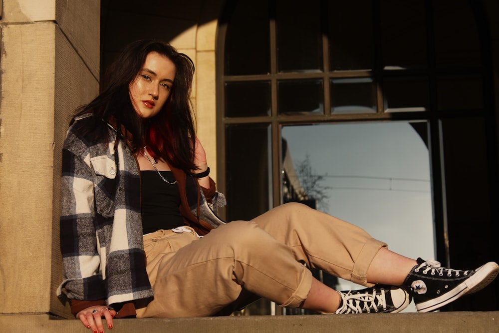 a woman sitting on the ledge of a building