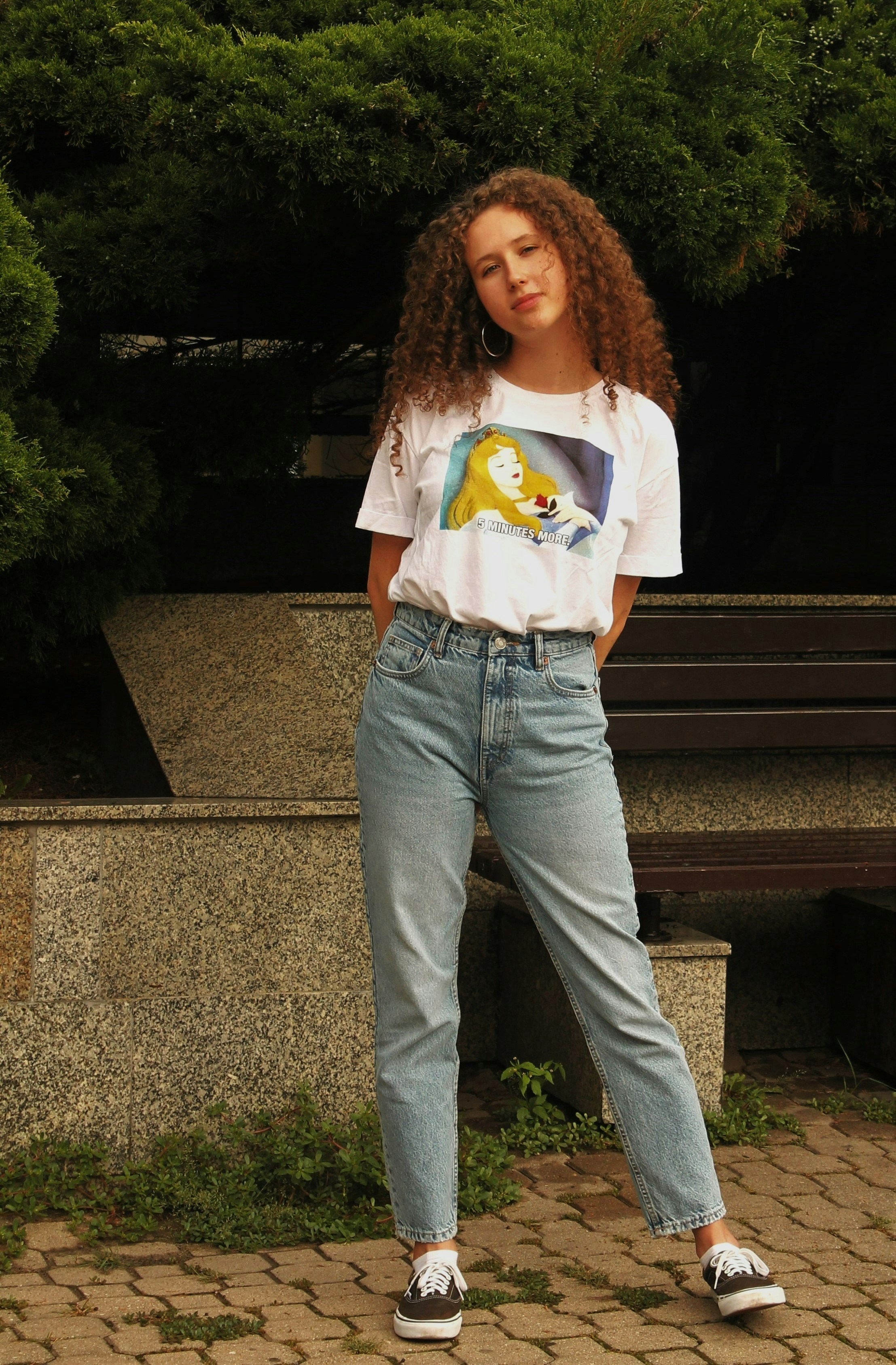 Una mujer parada en una pasarela de ladrillos junto a un banco