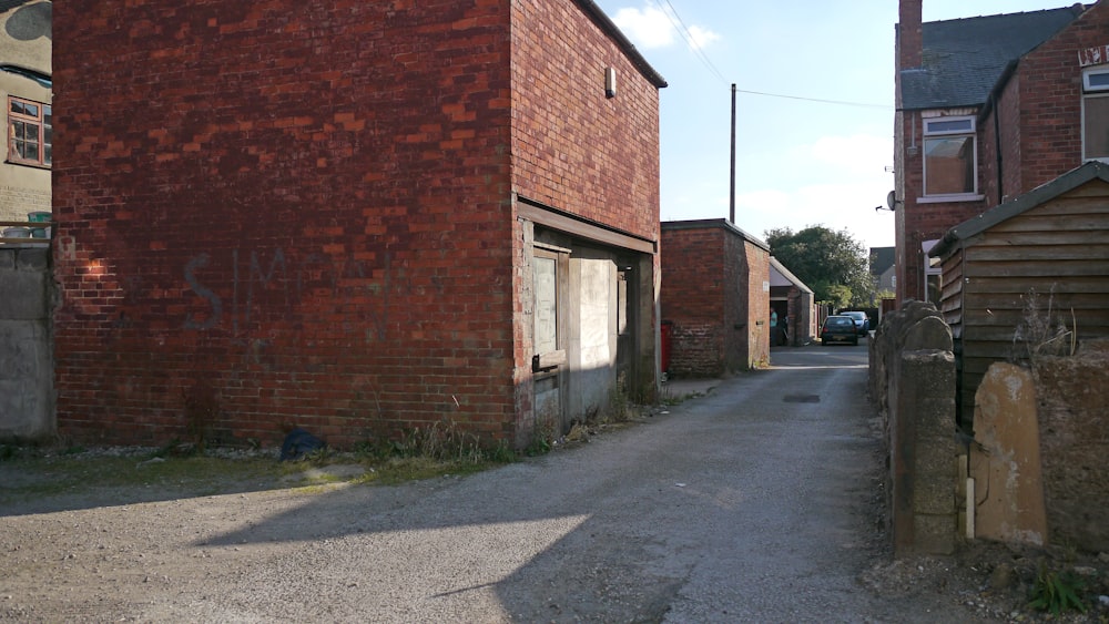 a brick building next to a street with a car parked in front of it