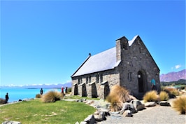 a small stone church with a lake in the background