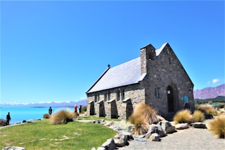 a small stone church with a lake in the background