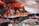 A bustling market scene with vendors and raw meat on display under orange umbrellas. People are busy arranging meat on tables, with plastic containers and various items around. Some stall lights hang overhead, illuminating the area.