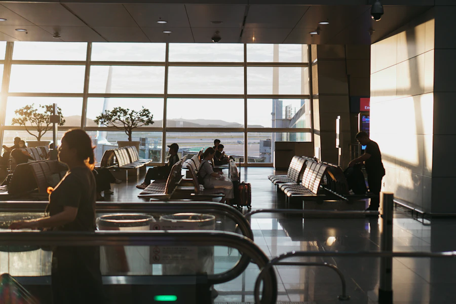 Departure lounge at sunset, passengers waiting in rows of seats beside floor-to-ceiling windows
