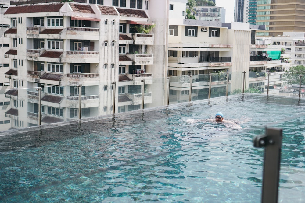 a person swimming in a pool in front of a building
