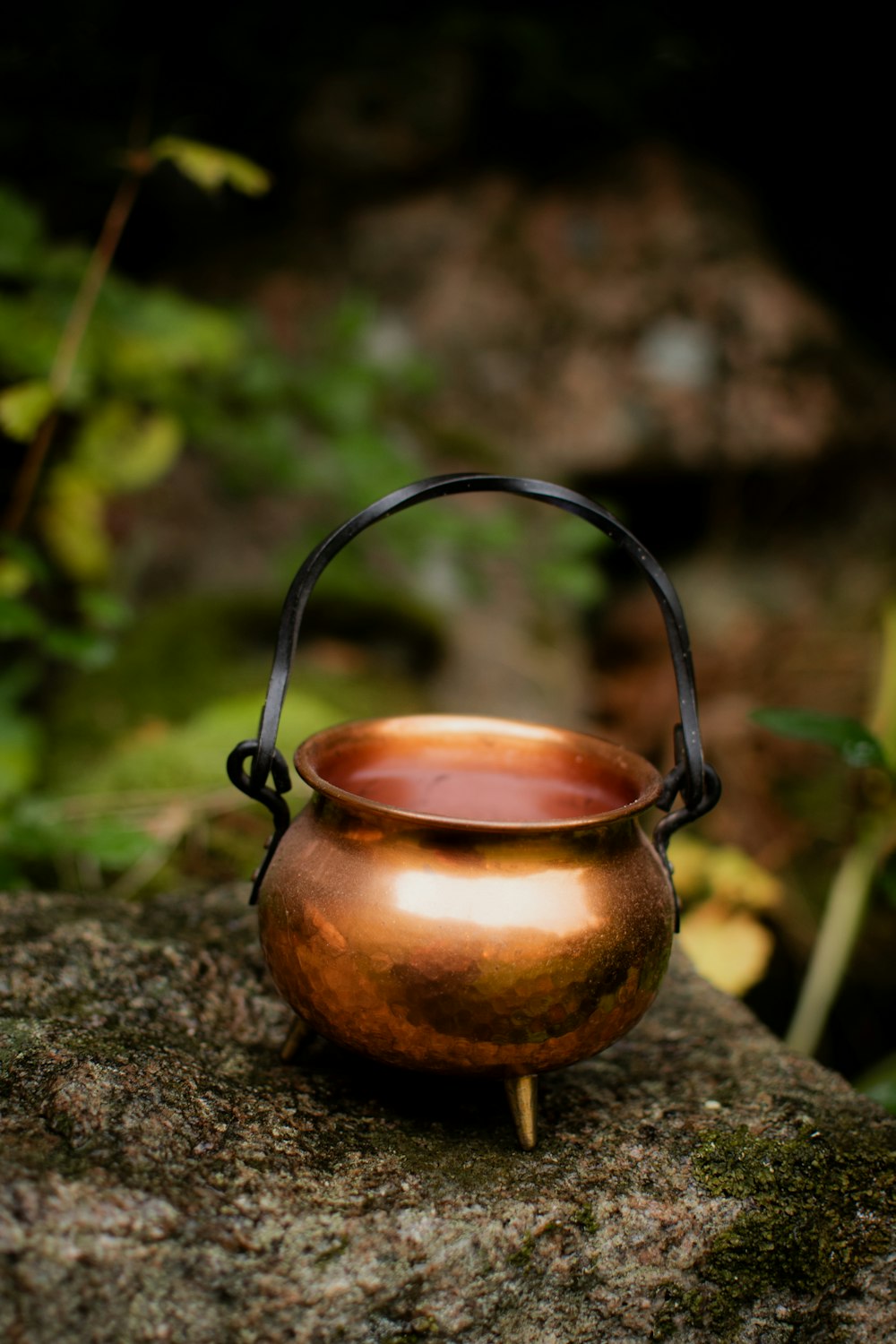 a metal pot sitting on top of a rock