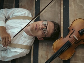 a man laying on the ground next to a violin
