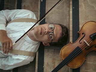 a man laying on the ground next to a violin