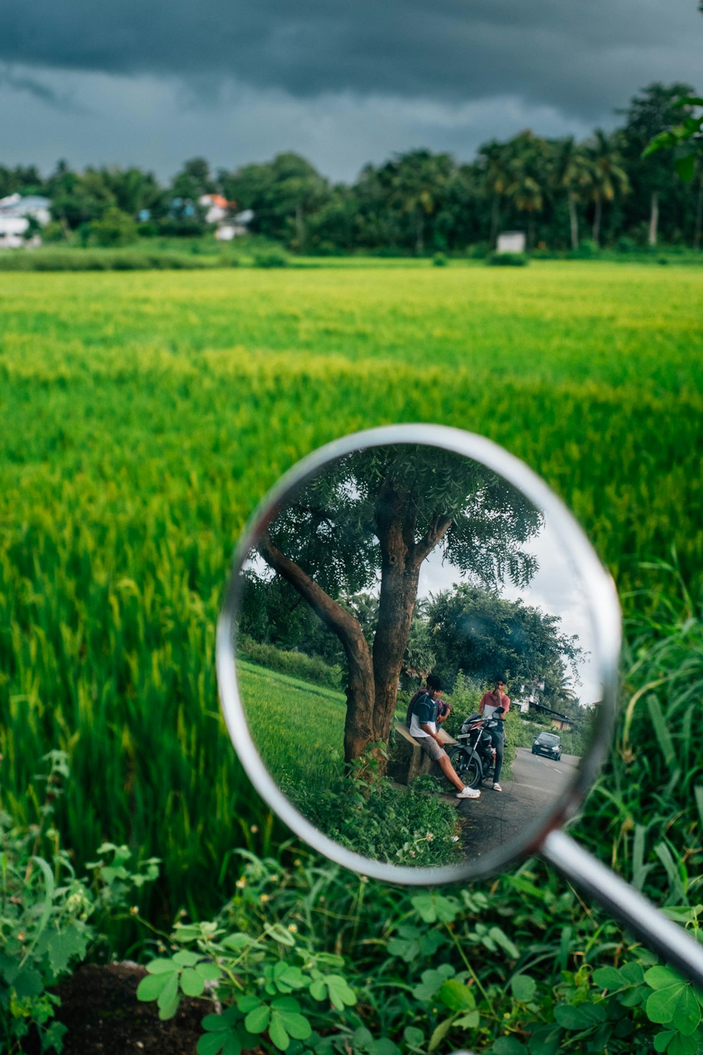 a magnifying glass with a reflection of people sitting on a bench in a