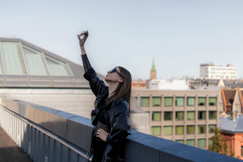 a woman standing on top of a roof with her arms in the air