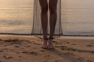 A serene moment of a dancer barefoot on sandy shore, bathed in golden light.
