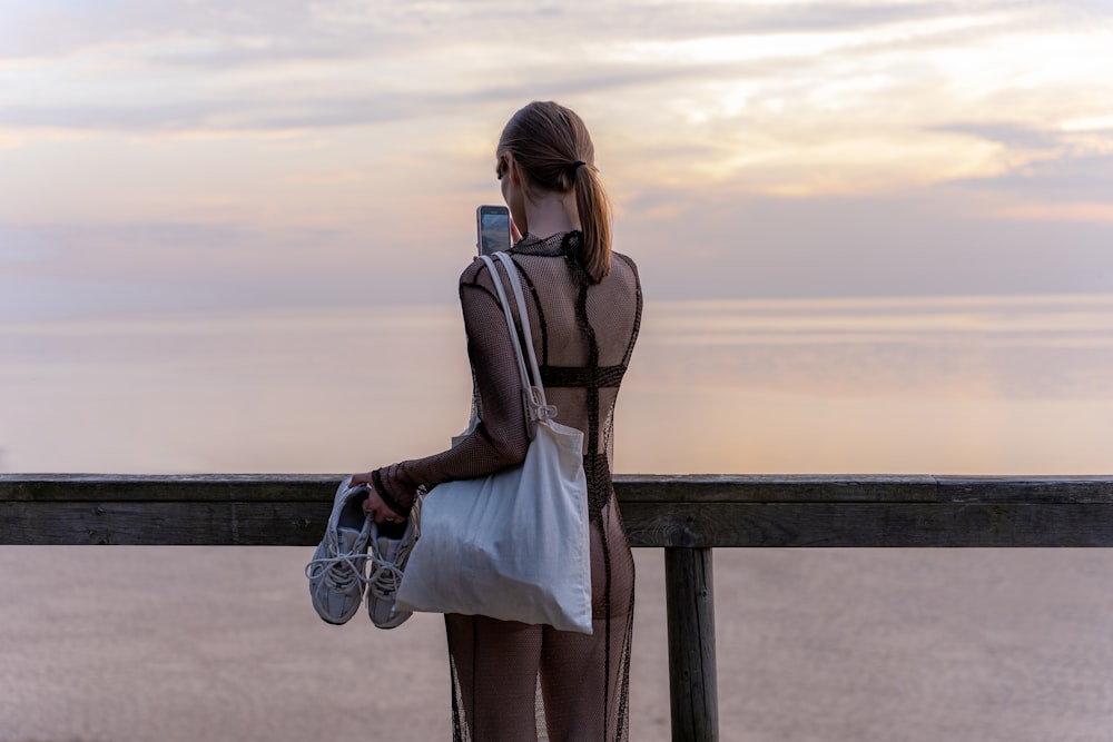 a woman standing on a pier holding a purse