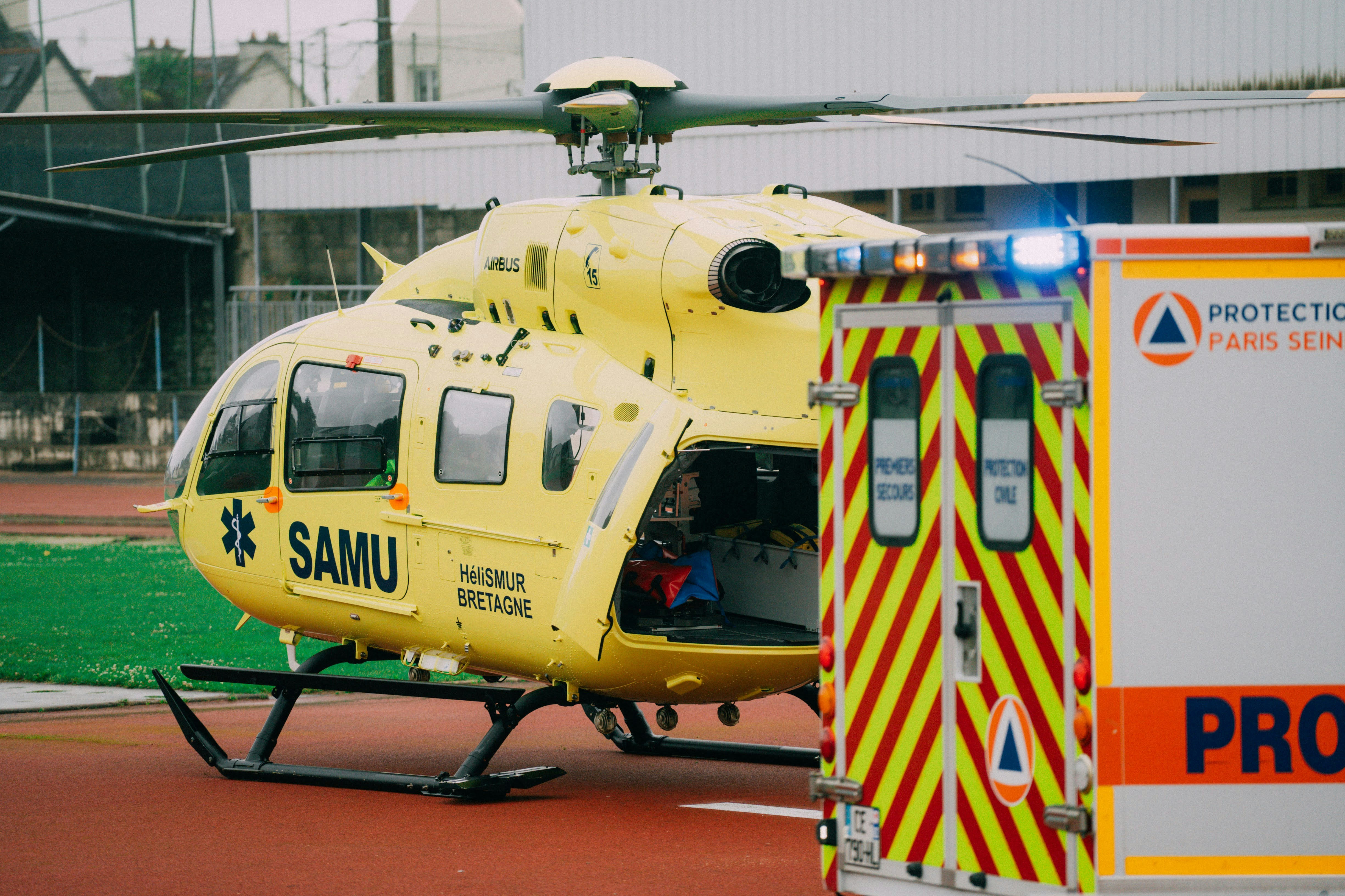 a large yellow helicopter parked next to an ambulance