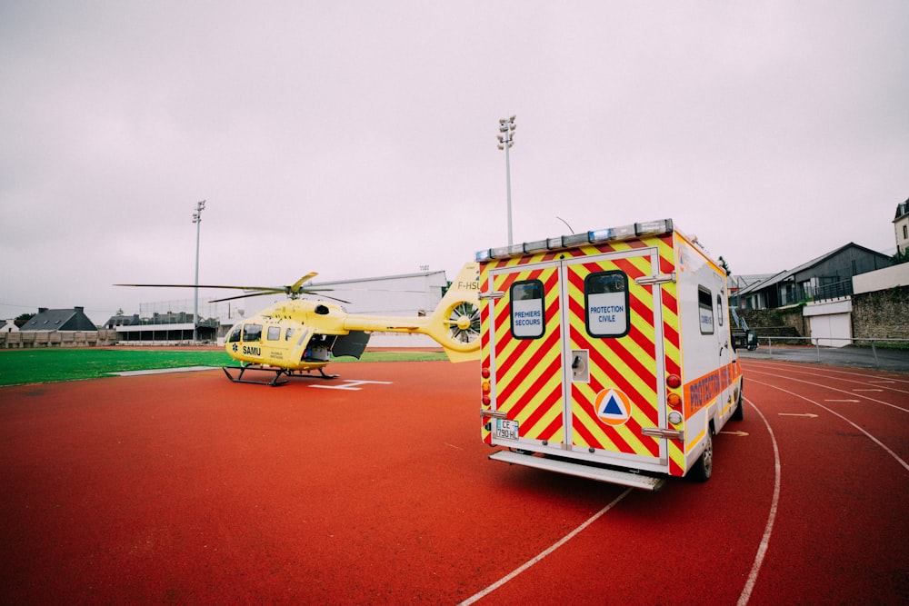 a yellow and red helicopter sitting on top of an airport tarmac