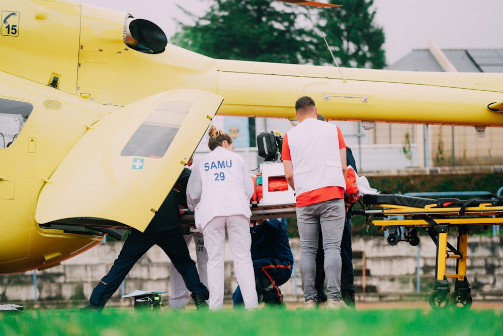 a group of people standing next to a yellow helicopter