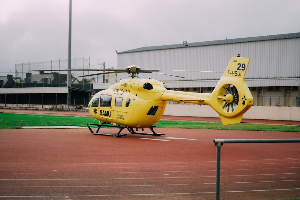 un hélicoptère jaune assis au sommet d’une piste