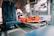 The interior of an emergency medical helicopter is shown with blue seating and a stretcher. Medical equipment and instruments are attached to the walls, alongside an orange survival kit on the stretcher. The atmosphere inside the helicopter is clinical and efficient, reflecting its use for medical emergencies.