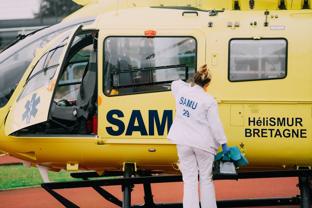 a woman standing in front of a yellow helicopter