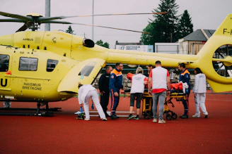 a group of people standing around a yellow helicopter