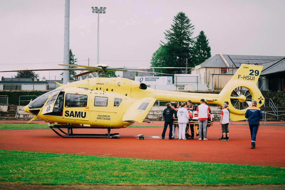 a group of people standing in front of a yellow helicopter