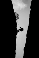 Instructor demonstrating rope rescue techniques on a cliffside during daylight.