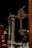 A close-up view of a metallic mechanical device featuring a chain and sprocket, springs, and various metal components. It appears to be part of a larger machinery or a musical instrument.