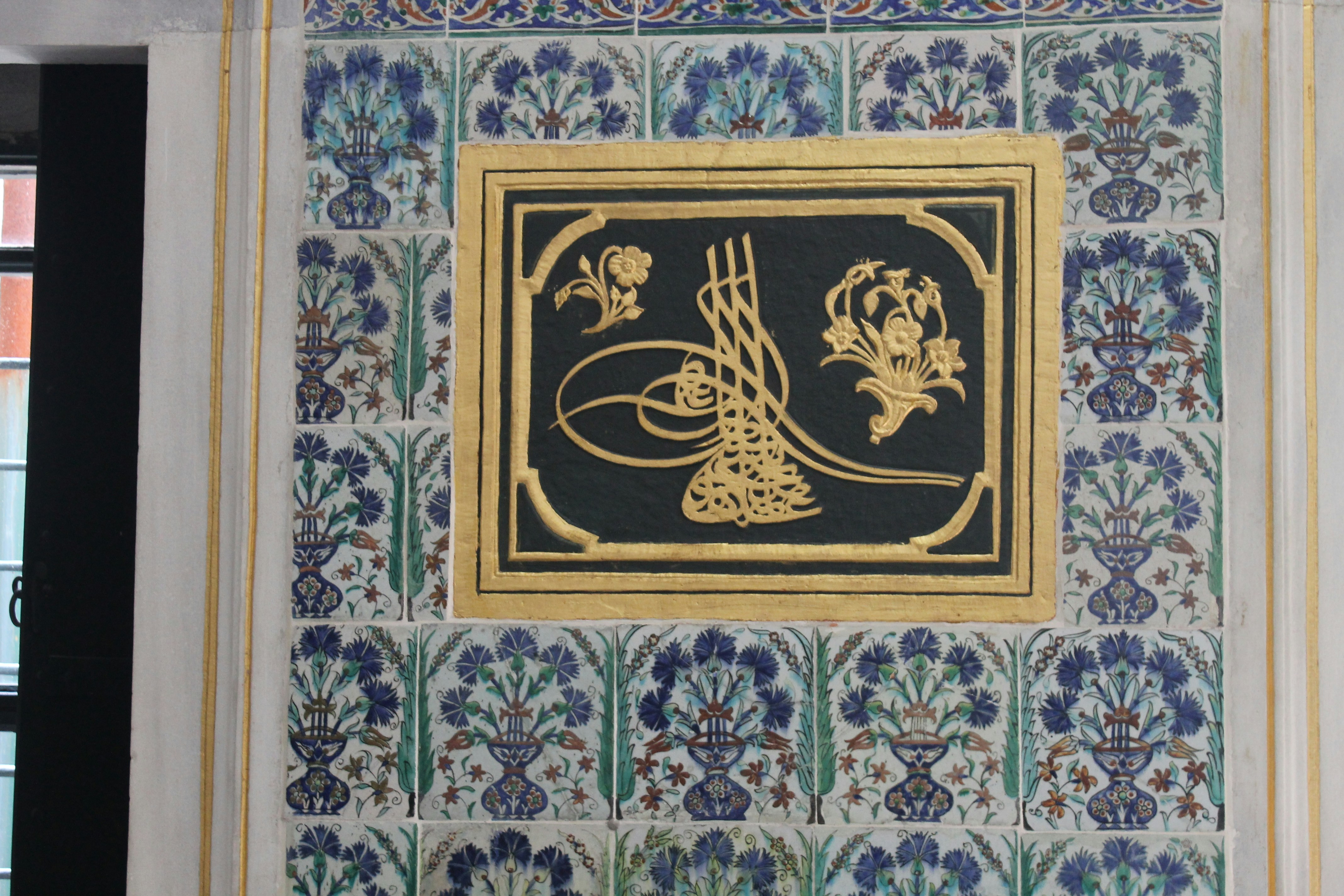 Intricately designed calligraphy art piece framed in warm beige and gold tones.