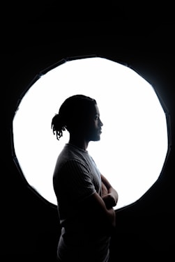 A serene person standing confidently with arms crossed, surrounded by soft glowing light symbolizing protection.