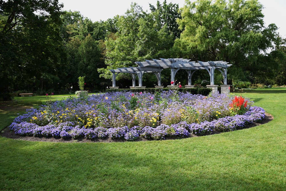 a flower garden with a gazebo in the middle of it