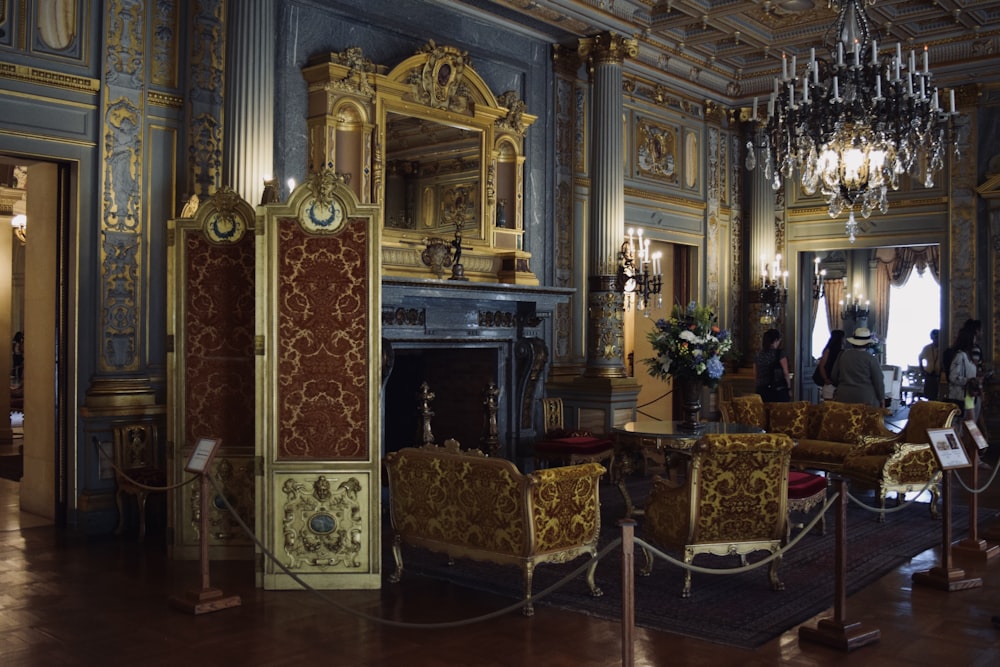 a room with a chandelier, chairs and a fireplace