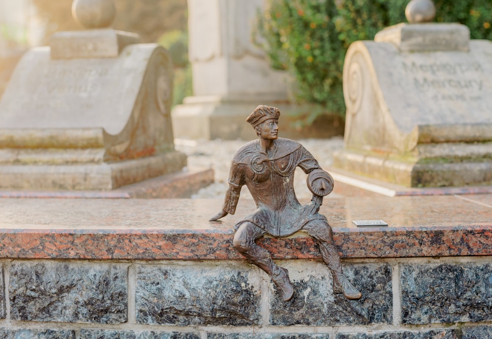 a statue of a woman sitting on top of a stone wall