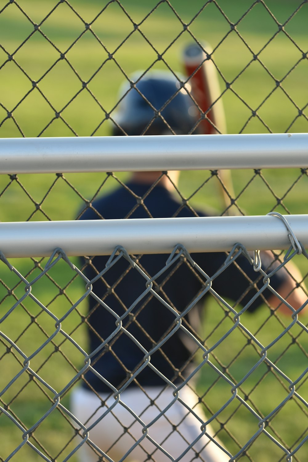 a baseball player holding a bat behind a fence