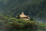 A peaceful temple nestled in the mountains, with monks meditating quietly in the early morning mist.