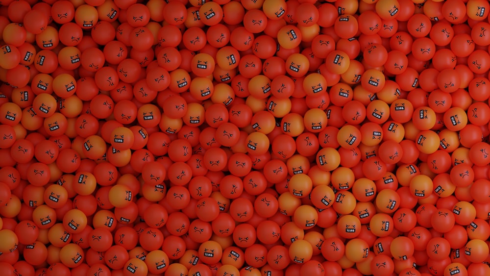 a large pile of oranges with faces drawn on them