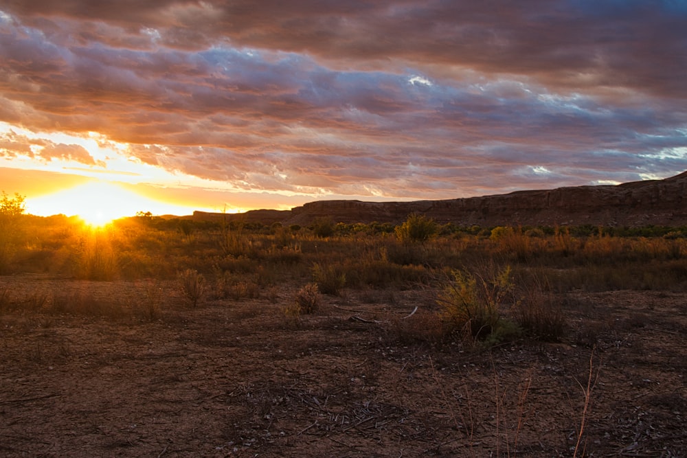 the sun is setting over a desert plain