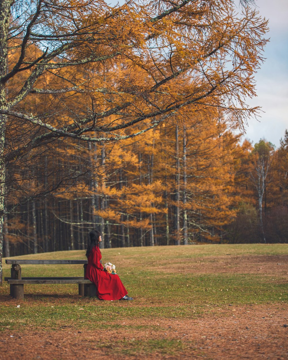 a woman in a red dress sitting on a bench