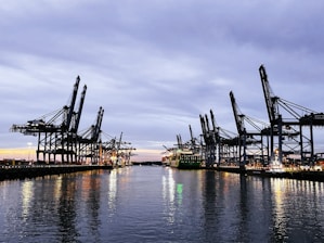 A vibrant sunrise over a bustling port with ships and cranes symbolizing sustainable maritime and industrial activity.