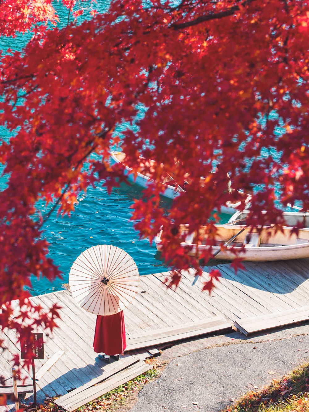 a woman holding an umbrella standing on a dock