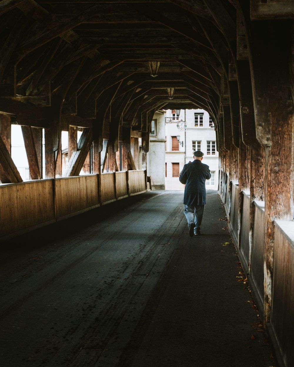 a man walking down a long wooden bridge
