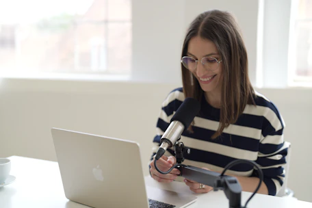 A smiling performer connecting with a global audience through a laptop camera in a cozy room.