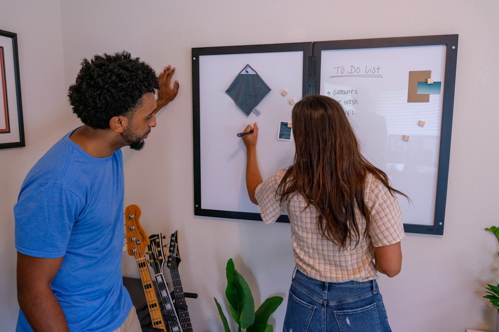 a man and a woman writing on a white board