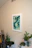 A softly lit corner of a living room featuring a framed abstract artwork with deep forest green and muted clay tones.