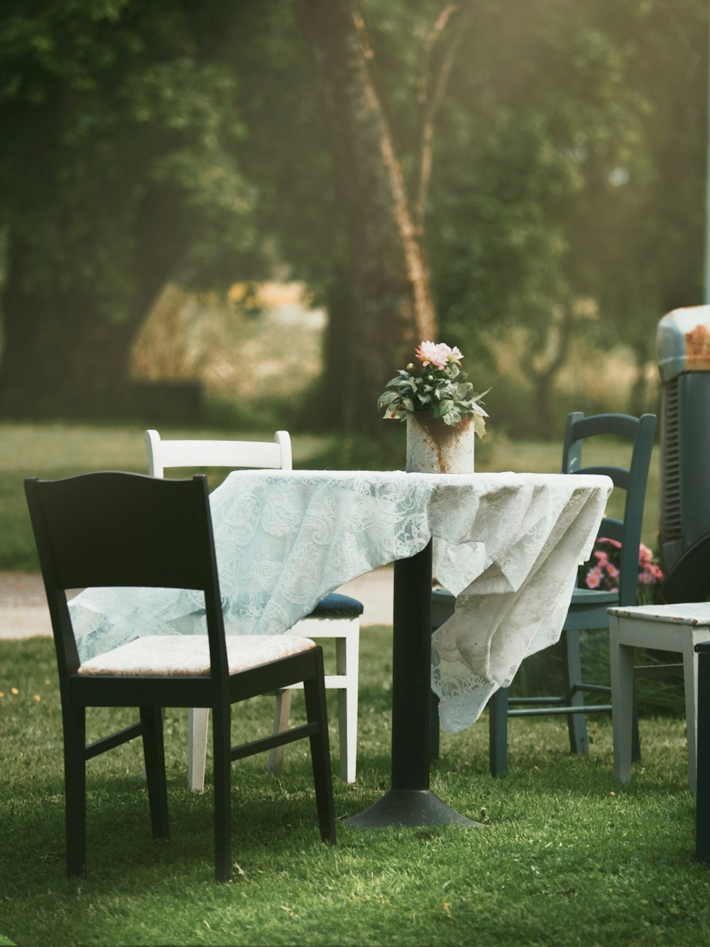a table and chairs in the grass with a vase of flowers on the table
