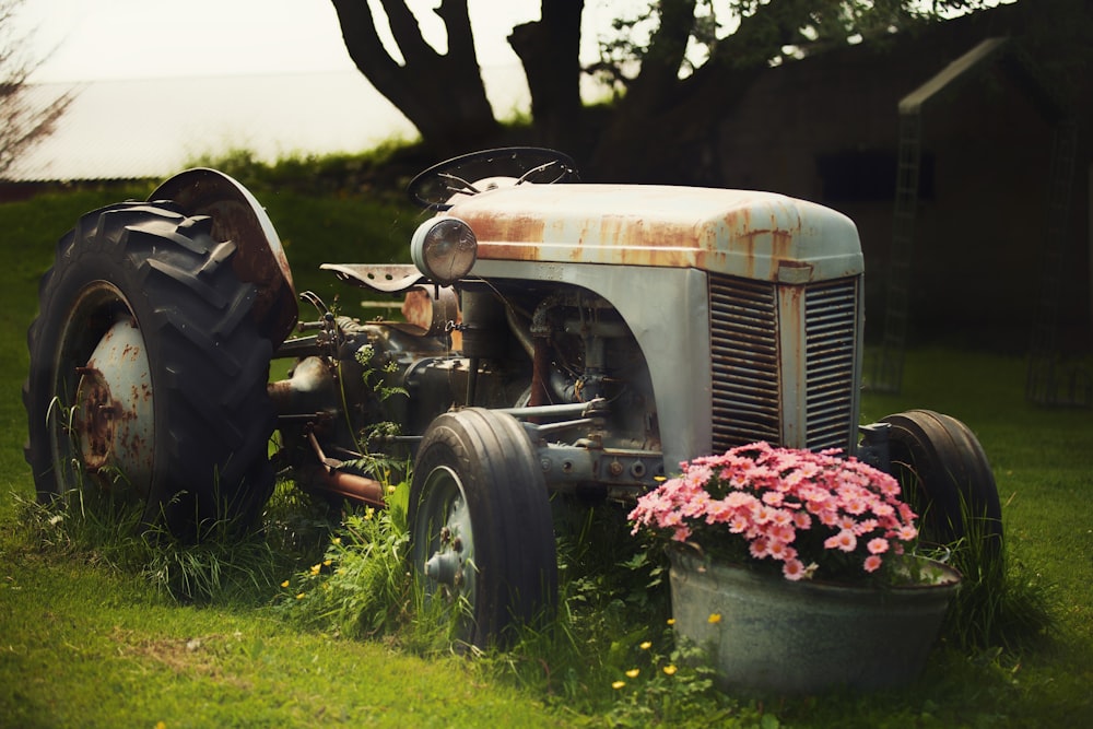 an old tractor with a flower pot in the grass