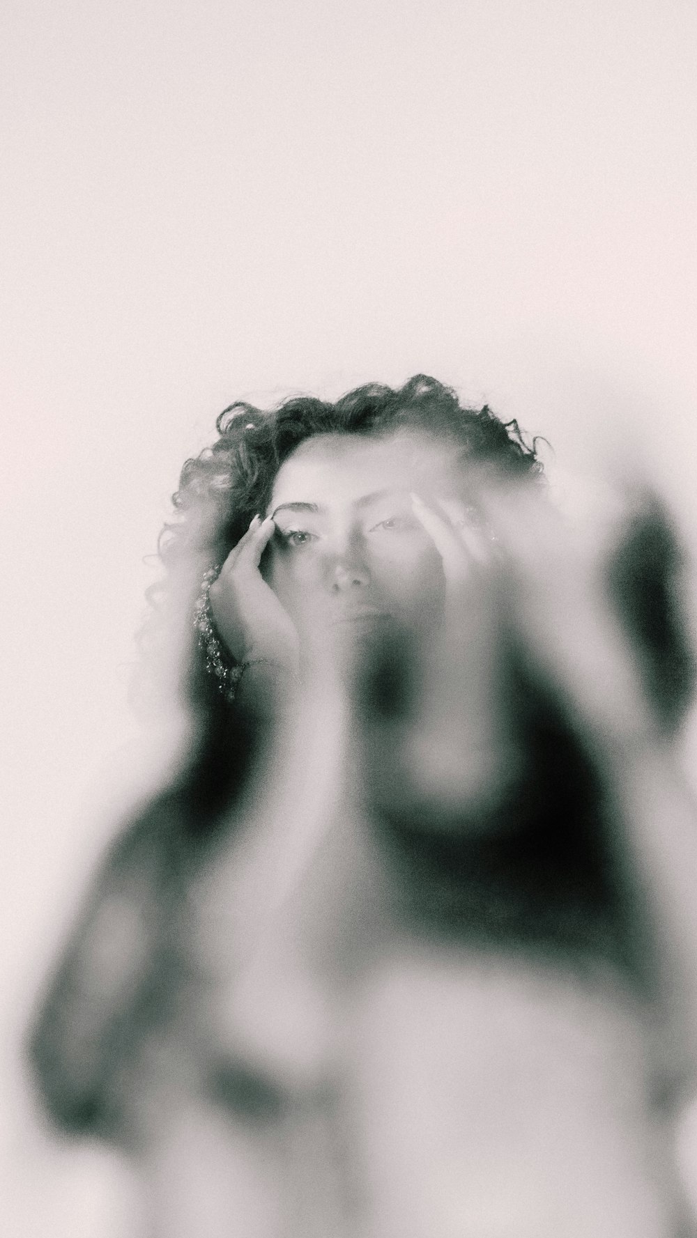 a black and white photo of a woman covering her eyes