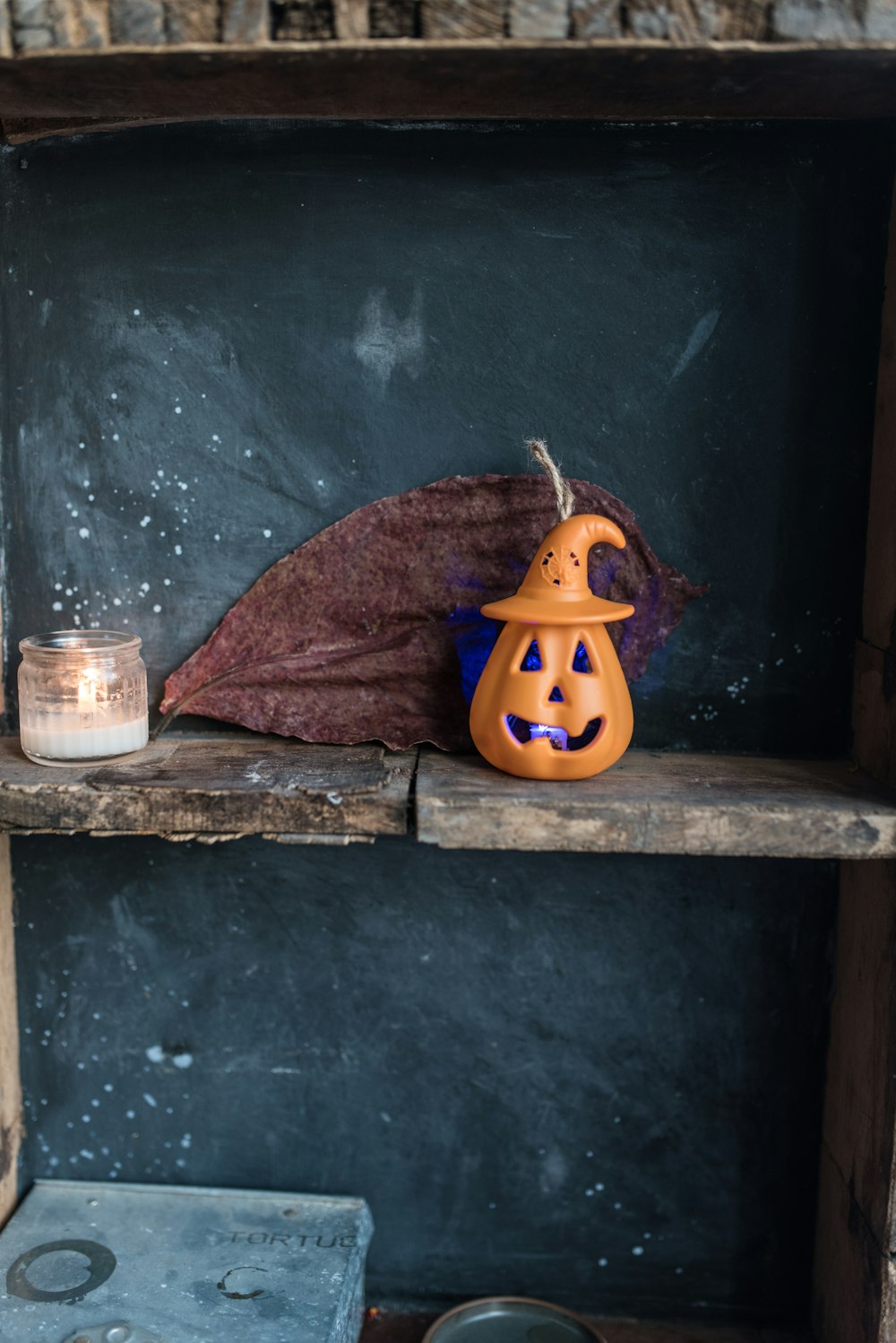 a halloween pumpkin sitting on a shelf with a candle