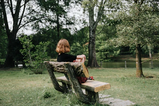 A thoughtful counselor speaking with a person sitting alone on a park bench.