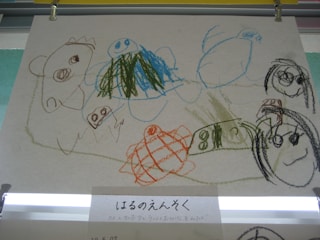 A child’s drawing rendered with colorful crayons on paper, depicting various playful and abstract figures including animals and objects. The artwork is simple, with scribbled lines and imaginative shapes. The picture features smiling faces and abstract forms, conveying a sense of creativity and innocence.