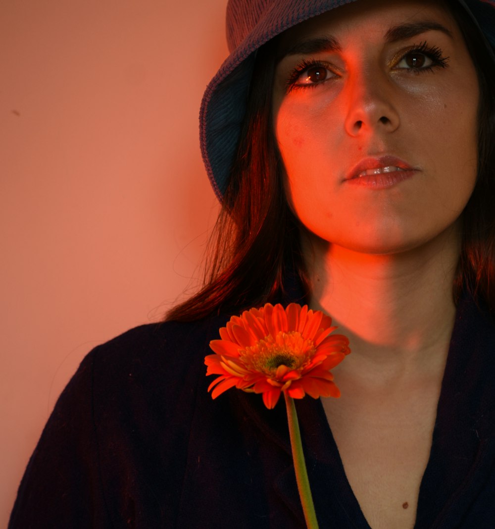 a woman wearing a hat and holding a flower