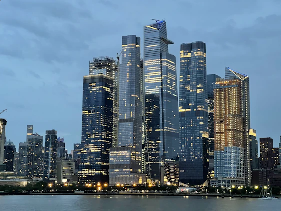 A sleek modern financial district skyline at dusk with digital data overlays representing global finance connections.