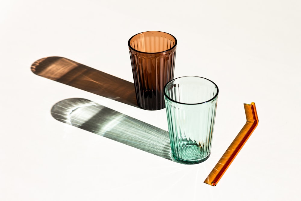three different colored glasses and a straw on a white surface